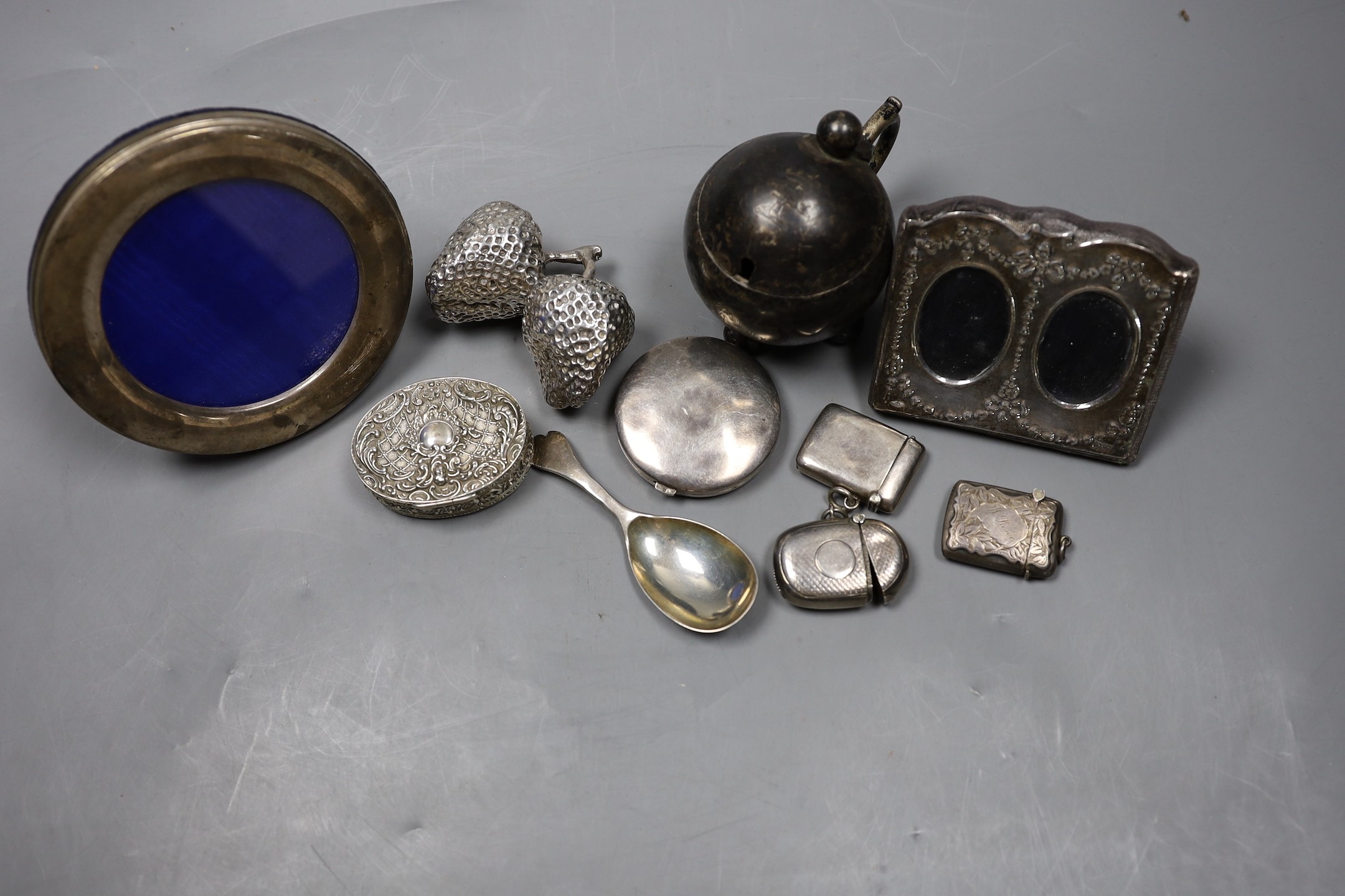 Sundry small silver including a Victorian globular mustard pot, two mounted photograph frames, three vesta cases, a caddy spoon, compact, circular white metal box and cover and a filled 'pair of strawberries' paperweight